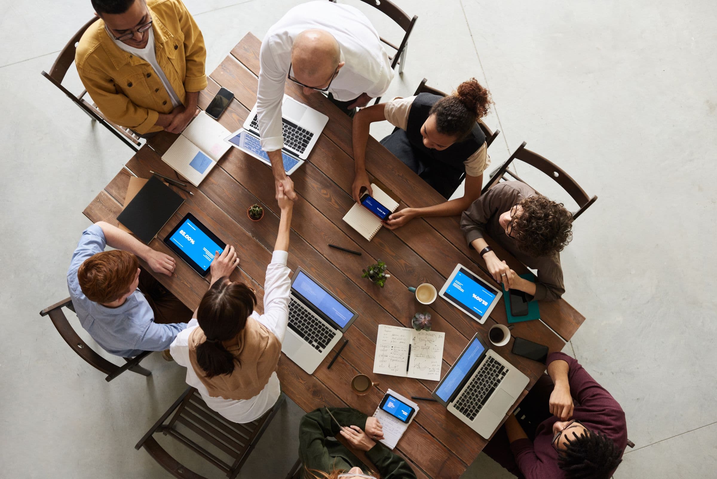 A recruitment team working around a shared table, reviewing notes and laptops together