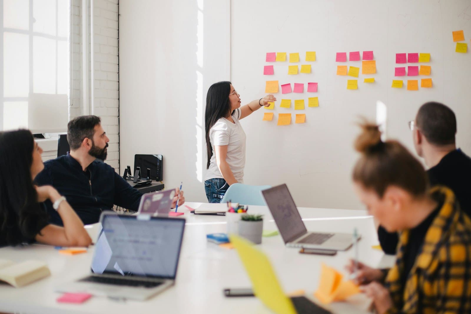 A recruiter mapping a hiring plan across a wall of notes while colleagues work